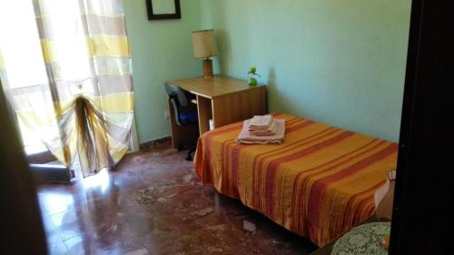 een slaapkamer met een bed, een bureau en een raam bij Casa Vacanze S.Andrea in Lascari