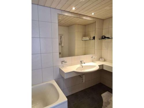 ein Badezimmer mit Waschbecken, Badewanne und Spiegel in der Unterkunft Holiday apartment I in Chalet Bodenwald in Grindelwald