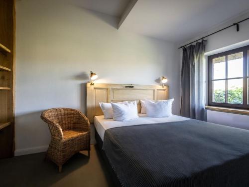 ein Schlafzimmer mit einem Bett mit einem Stuhl und einem Fenster in der Unterkunft Superior Studio in the Manor House in Bastorf