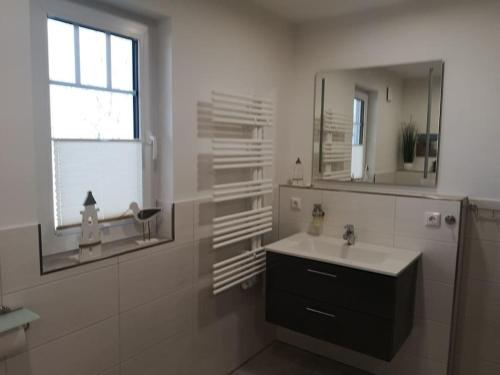 Un baño blanco con lavabo y espejo. en Hannes' thatched house on Rügen, en Mellnitz