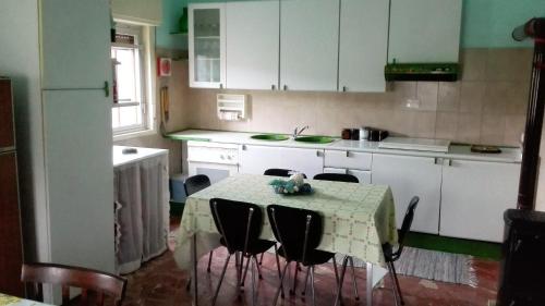 ラスカリにあるCasa Vacanze S.Andreaのテーブルと椅子付きのキッチン、白いキャビネット付きのキッチン