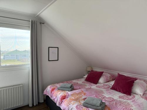 a bedroom with a bed with pillows and a window at Holiday home in Makkum with swimming pool in Holle Poarte