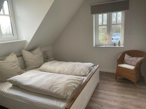 a bed with white sheets and a chair in a room at The Linnebargs, House 4 in Bisdorf