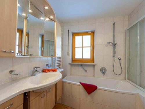 een badkamer met een bad, een wastafel en een douche bij House Alpenlicht in Reit im Winkl