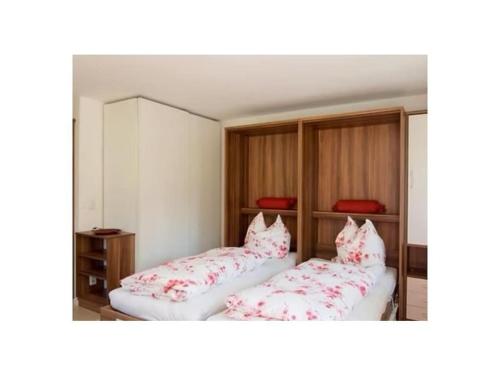 Holiday apartment with 1 bedroom في Kirchberg: سريرين في غرفة مع وسائد حمراء وبيضاء