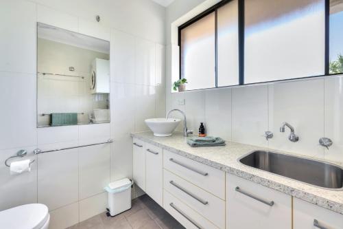 un bagno bianco con lavandino e WC di Ocean Vista Nightcliff Foreshore Apartment a Nightcliff