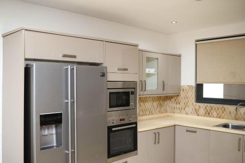 una cucina con elettrodomestici in acciaio inossidabile e armadietti bianchi di Premier Place-BlueWaters Property Management LTD a Accra