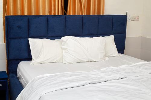 Bett mit blauem Kopfteil und weißen Kissen in der Unterkunft Royal prima guest house, apartment and event center in Amanfro
