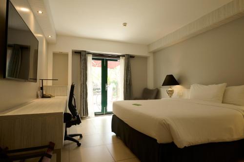 Una habitación de hotel con una cama, un escritorio y una ventana. en Royal Torarica, en Paramaribo