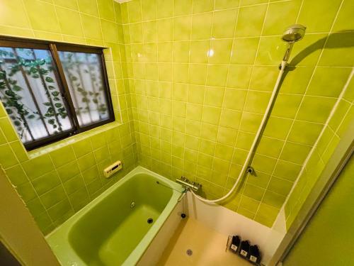 a green bathroom with a tub and a window at Ichiedo - Private House for Up to 5 Guests 2-min walk from Station いちえ堂 - 5名様まで貸切 駅徒歩2分 in Kashihara