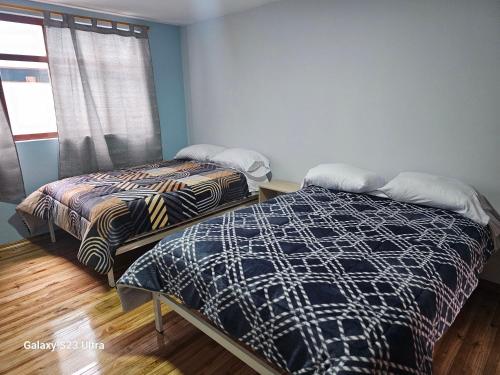 two beds sitting in a room with a window at Hospedaje Familiar Ecuador in Cuenca