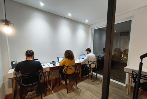 um grupo de pessoas sentadas em uma mesa com laptops em Hobi Hostel Boutique em São Paulo
