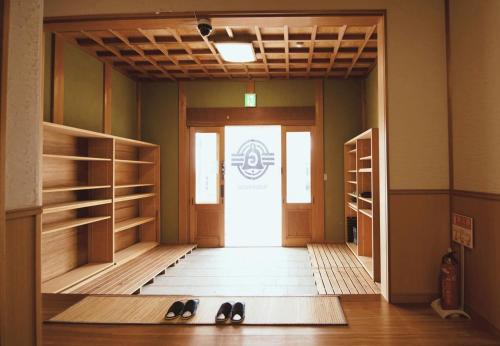 Un pasillo con una puerta con un par de zapatos. en 鈴籠城 籠の間 ダブルベッド2台 二段ベッド1台, en Nagahama