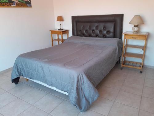 een bed in een slaapkamer met 2 nachtkastjes en 2 tafels bij La Morada de tus Sueños VCP con vista al LAGO in Villa Carlos Paz