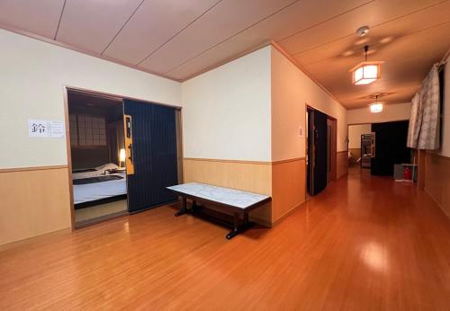 ein leeres Zimmer mit einer Bank auf einem Holzboden in der Unterkunft 鈴籠城 全室貸切 各部屋ダブルベッド2台 in Nagahama
