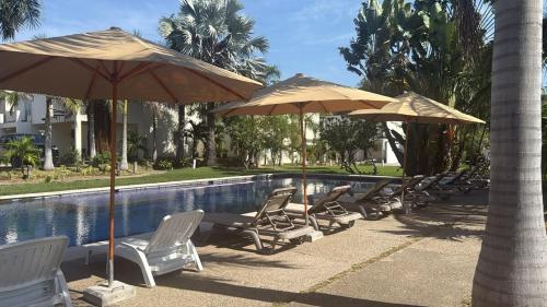 eine Gruppe von Stühlen und Sonnenschirmen neben einem Pool in der Unterkunft La casa blanca in Mezcales