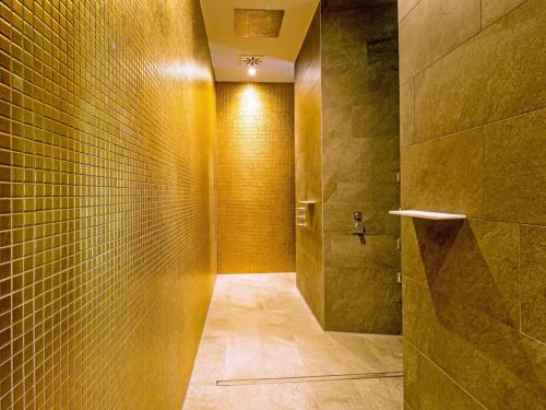 a bathroom with a walk in shower with yellow tiles at Dream holiday apartment with pool sauna MB in Börgerende-Rethwisch