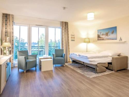 a bedroom with a bed and two chairs at Dream holiday apartment with pool sauna MB in Börgerende-Rethwisch