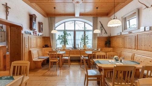 a restaurant with wooden tables and chairs and a large window at Hotel Forchhammer in Pliening