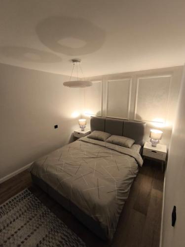 a bedroom with a bed with two lamps on it at Pri Home in Pristina