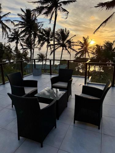 a patio with chairs and tables and palm trees at Kaas Villas - Entire Two Bedroom Villa With Private Pool & Garden in Dickwella