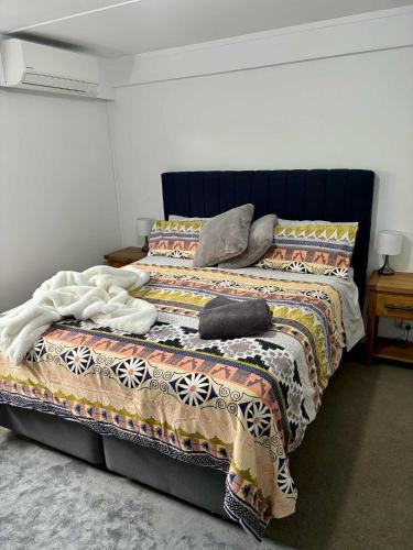 a bed with a blanket and pillows on it at Kiwi Cove in Tauranga