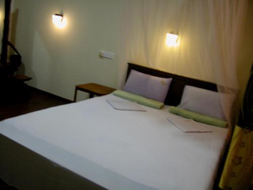 a bedroom with a large white bed with two pillows at Sigiri Lion Lodge in Sigiriya