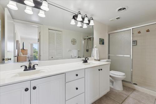 een witte badkamer met 2 wastafels en een toilet bij Windrush 509 in Cocoa Beach