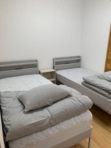 Dos camas en una habitación con paredes blancas. en hostel 丹鶴, en Shingu