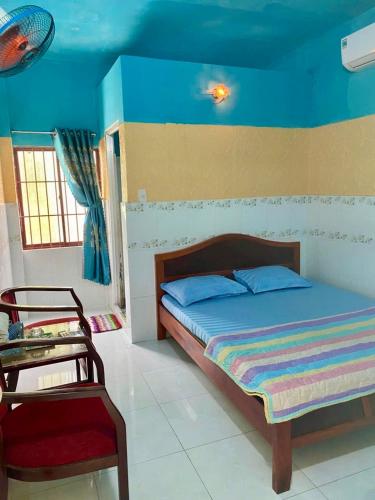 a bedroom with a bed and a chair at Song Anh Mui Ne Guesthouse in Mui Ne