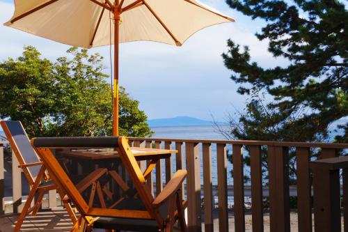 a table and chair with an umbrella on a deck at ふとの情景 Futo Nostalgia in Ito