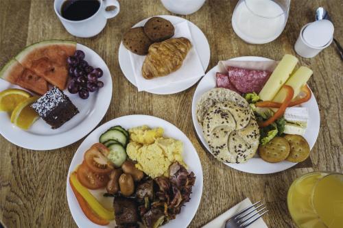 ベルゲンにあるマジック ホテル ソルハイムスビケンの白い皿に食べ物が盛られたテーブル