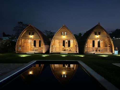 a couple of houses with a reflection in the water at night at Villa Aiden Bungalow 2 near Beach in Ungasan
