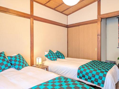 due letti con lenzuola a quadri in una stanza di ann近島 無料駐車場2台 階段なし安心の平屋貸切 ファミリーやグループ旅行に最適 a Gifu