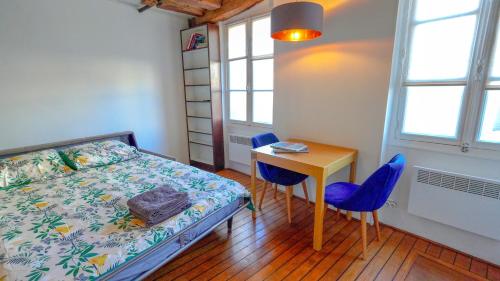 Un dormitorio con una cama y una mesa y sillas. en 12 Lovely Studio Steps from Boulevard Saint Germain, en París