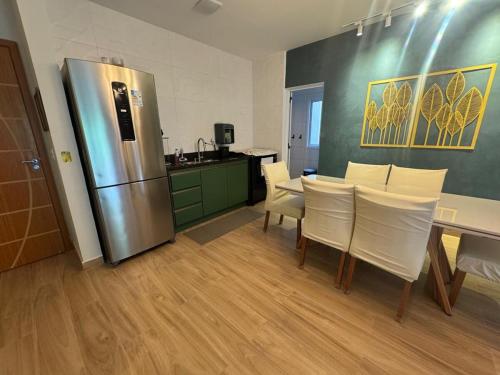 une cuisine avec une table et un réfrigérateur en acier inoxydable dans l'établissement Apartamentos das Toninhas, à Ubatuba