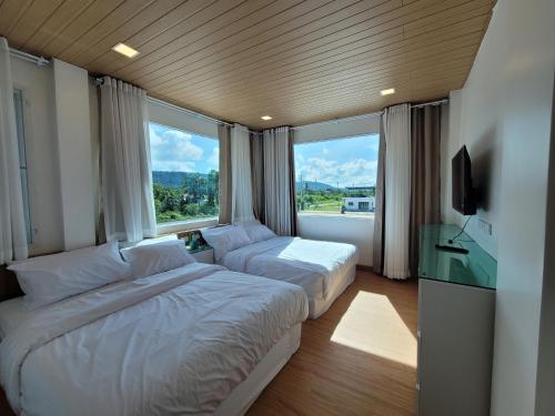una camera d'albergo con due letti e una televisione di The wide pool villa trat a Ban Nong Wiwat