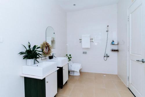 a white bathroom with two sinks and a toilet at Kegotel Luxury Villa - Bãi Tắm Long Cung in Vung Tau