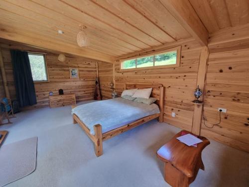 a bedroom in a log cabin with a bed at Sub-Tropical Paradise Retreat Willow Creek Cabin with Access to Sauna in Totara North