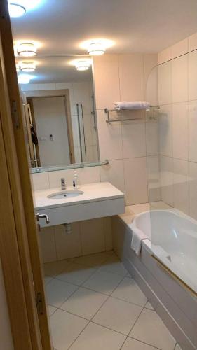 a bathroom with a sink and a tub and a mirror at Vila verde Resort in Santa Maria