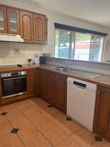 una cucina con armadi in legno e lavastoviglie bianca di Cheerful 2 bedroom townhouse with secure parking a Mildura