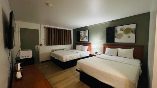 Una habitación de hotel con dos camas y un televisor. en Nelson Hotel, en Swan River