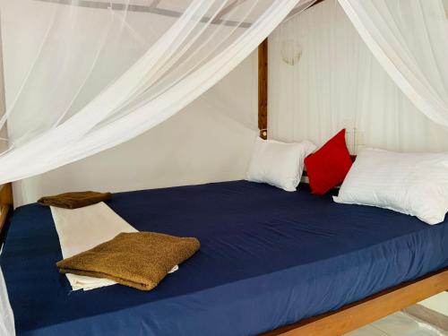 a bedroom with a blue bed with white and red pillows at Calidan in Mirissa