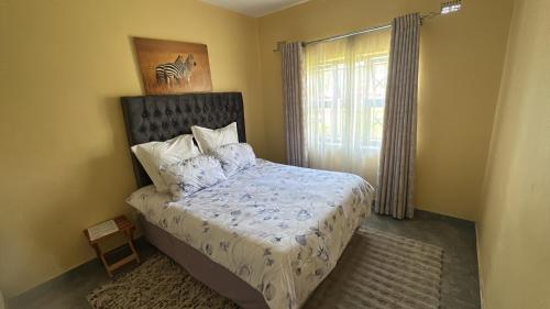 ein Schlafzimmer mit einem Bett und einem Fenster in der Unterkunft Hatfield staylax Manor 2 in Harare