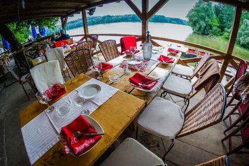 a table with red napkins and chairs on a boat at Guest house Pikec in Bezdan