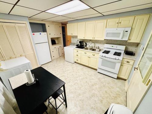 Una cocina con electrodomésticos blancos y una mesa negra. en Charming Cape Cod Home in Glen Burnie, MD, en Glen Burnie