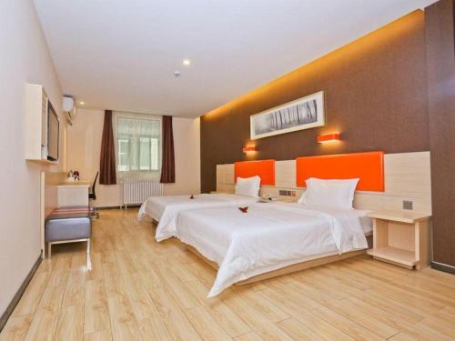 济南7 Days Premium Jinan Gaoxin Qu Wanda Plaza的酒店客房设有两张床和橙色的墙壁。