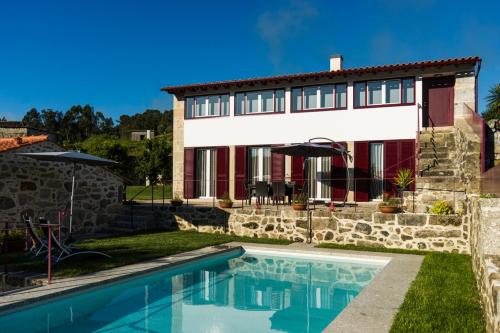 a house with a swimming pool in front of a house at Quinta do Cerqueiral in Arcos de Valdevez