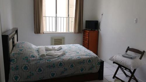 a bedroom with a bed and a window and a chair at Kitinet na Praia de Botafogo in Rio de Janeiro