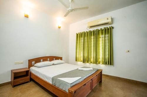 a bedroom with a bed and a window with a fan at Marari Oommen's Villa in Vayalār